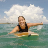 Happy surfer in the water paddling towards the camera